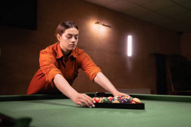 Genç bir kadın yeşil masaya bilardo toplarını üçgen içine koydu. Top, bilardo, bilardo ve bilardo konsepti