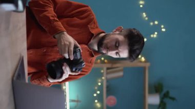 Genç ve mutlu fotoğrafçı elinde bir DSR kamera tutuyor ve resimlerine bakıyor. Yeni bir proje üzerinde çalışırken yaratıcı erkek fotoğrafçı ya da serbest çalışan biri. Dikey video