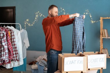 Erkekler evdeki eşyaları düzenler ve katlar, bağış kutusu için kıyafet toplarlar. Geri dönüşüm ve bağış kavramı