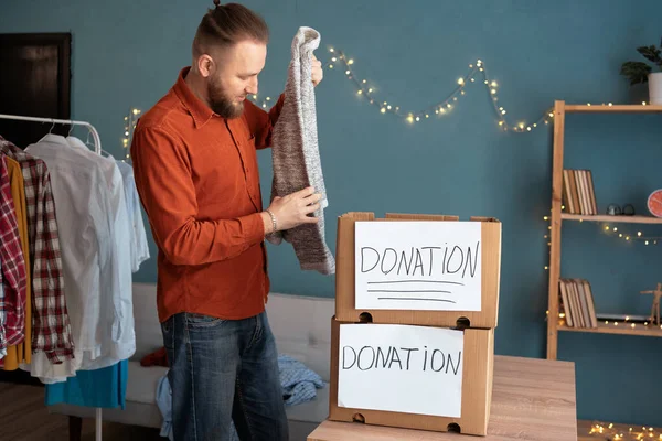 一个英俊的男人把捐款箱装进了他家里的办公室 为穷人准备衣服 捐赠概念 — 图库照片