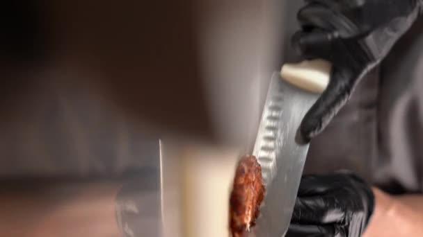シェフはまな板の上のキッチンでフライドチキンフィレをナイフで切ります 肉と一緒に夕食を調理の背景 食べ物の概念 垂直ビデオ — ストック動画