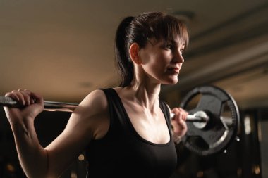 Spor salonunda spor salonundaki spor salonundaki spor salonunda spor yapan kadın. Kadın, ağır ağırlıklarla egzersiz yaparken çaba sarf ediyor. Boşluğu kopyala