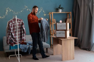 Evdeki bağış kutusuna kıyafet paketleyen bir adam. Bağış konsepti. Boşluğu kopyala