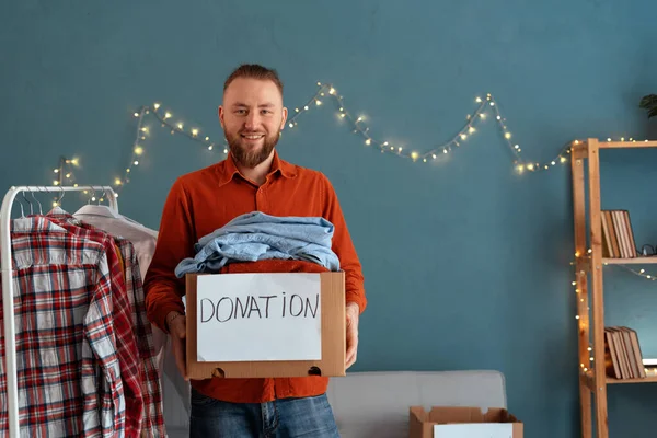Ofisinde bağış kutusu olan mutlu genç bir adam. Bağış konsepti. Boşluğu kopyala