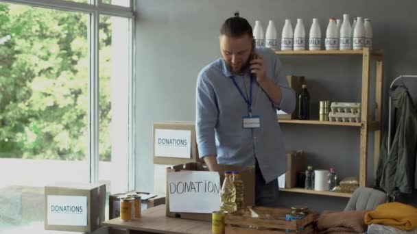 Heureux Volontaire Masculin Parlant Téléphone Mettant Nourriture Dans Boîte Don — Video