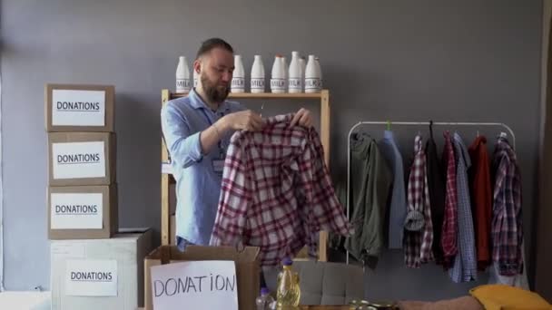 Jeune Homme Travaillant Centre Bénévolat Mettre Des Vêtements Dans Boîte — Video
