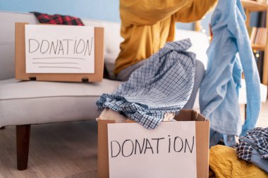 Bağış Konsepti. Kullanılmış eski kıyafetlerini bağış kutusuna hazırlayan kadının yakın çekimi.