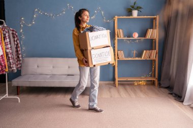 Ofisinde bağış kutuları olan genç bir kadın. Bağış konsepti. Boşluğu kopyala