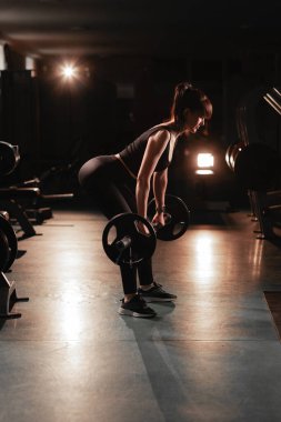 Spor salonunda spor yapan spor salonundaki halterci kadın halterlerle çömeliyor. Halter konsepti. Boşluğu kopyala