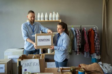 Gönüllü adam, iş arkadaşına bir kutu yiyecek dağıtım ya da mülteci yardım merkezinde veriyor. Sadaka, bağış ve gönüllülük konsepti