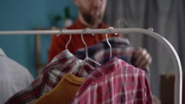 Odasında bağış kutusunu toplayan fakir insanlara yardım etmek için eski kıyafetleri seçen yakışıklı bir adam. Gönüllü çalışma, bağış ve kıyafet geri dönüşümü kavramı.