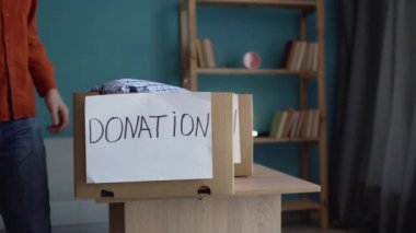 Bağış konsepti. Kıyafetlerle dolu bağış kutusunu tutan ve kameraya gülümseyen yakışıklı bir adam. Boşluğu kopyala