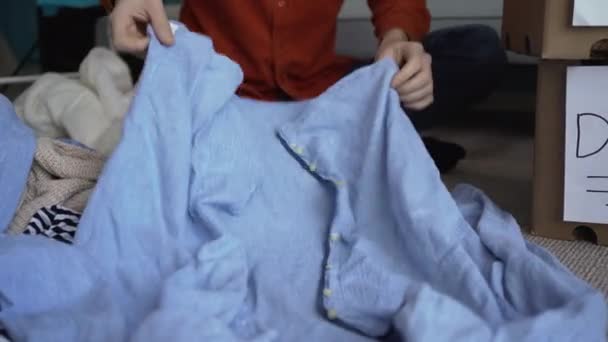 寄付品の入った箱に服を入れる男 ボランティアのコンセプト — ストック動画
