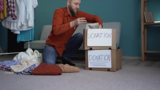 髭の男は床に服を着た貧しい人々のための寄付箱を準備します 寄付とボランティアのコンセプト — ストック動画