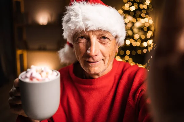 Mutlu Noel Baba Şapkalı Elinde Telefon Elinde Şekerlemeyle Fincanı Gösteriyor — Stok fotoğraf