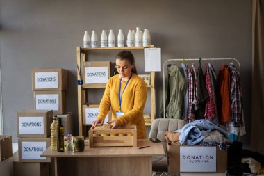 Sosyal hizmet görevlisi. İnsani yardım projesinde çalışan bir kadın. Evsizler barınağı. Bağış kutusu ve yiyecek. Boşluğu kopyala