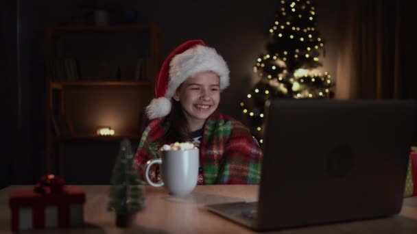 마시멜로를 즐거운 소녀가 저녁에 집에서 컴퓨터로 크리스마스 코메디 영화를 웃는다 — 비디오
