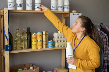 Mülteci yardımı ya da bağış merkezinde çalışan gönüllü bir kadın kutuda yiyecek paketliyor. Sadaka, bağış ve gönüllülük konsepti