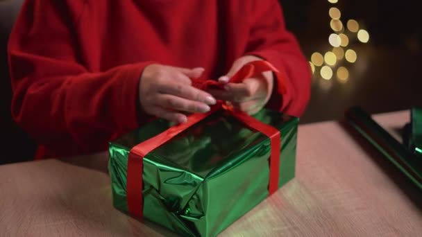 一个女人的手把礼物包起来 并在圣诞礼物上系上一条带子 系在蝴蝶结上的头像 圣诞礼物概念 — 图库视频影像
