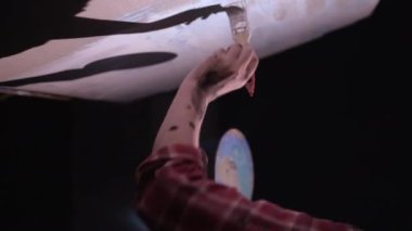 Kadın sanatçı elinin yakın çekimi, boya fırçası ve palet tutmak, yağlı boya resim çizmek. Ressam modern bir sanat eseri yaratıyor. Dikey video