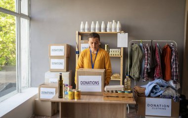 Dağıtım ya da mülteci yardım merkezinde yiyecek kutusunda çalışan genç ve mutlu bir gönüllü. Sadaka, bağış ve gönüllülük konsepti. Boşluğu kopyala