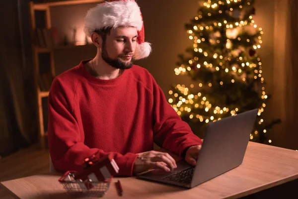才能とラップトップを持つ若い髭の男 クリスマス休暇でオンラインショッピング 自宅のオフィスで働いているフリーランスの男 ノートパソコンに入力する男性 クリスマスの瞬間 スペースのコピー — ストック写真