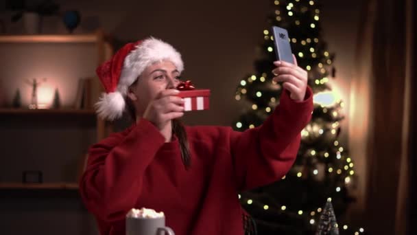 Joven Mujer Feliz Mostrando Regalo Navidad Mientras Recibe Una Videollamada — Vídeos de Stock