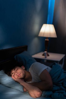 İyi uyku konsepti. Yakışıklı genç adam evde tek başına rahat bir yatakta uyuyor, ortopedik yatağının ve yastığının tadını çıkarıyor, fotokopi alanı.