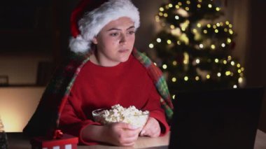 Genç bir kadın korku filmi izliyor, Noel arifesinde yüzünü korku içinde saklıyor, çevrimiçi film hizmeti kavramı. Boşluğu kopyala