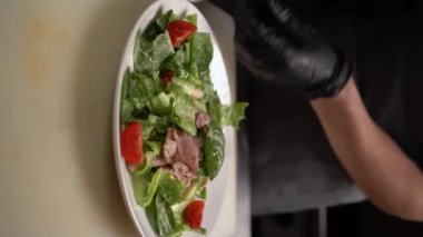 Sezar salatası pişiriyorum. Aşçı salata tabağına kızarmış ekmek ekler. Lezzetli bir restoran yemeği. Ev mutfağı. Kutlama salatası. Dikey video