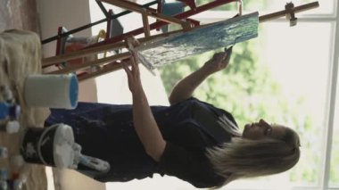 Yaratıcı sanat eserleri. Güzel sanatlar dersi. Renkli boyaları ve palet bıçağıyla çizen kadın. Dikey video