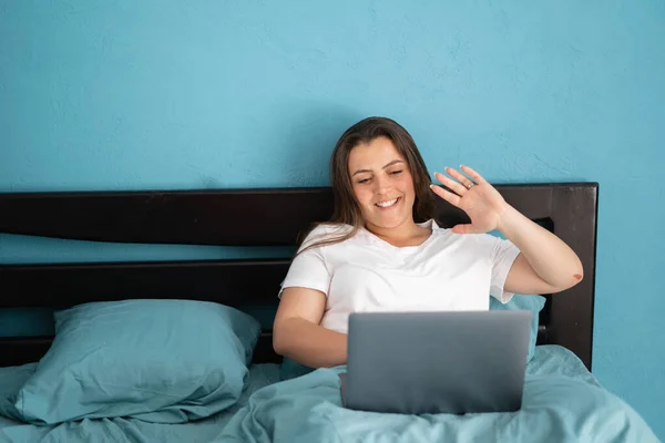 Молода Жінка Сидить Ліжку Має Відеодзвінок Ноутбук Щаслива Дівчина Махає — стокове фото