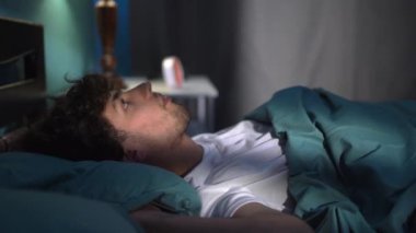 Uykusuzluktan muzdarip genç bir adam gece yatağında bir battaniyeyle yatar ve gecenin bir yarısı uyumaya çalışır. Boşluğu kopyala