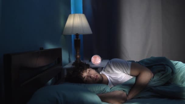 夜は居心地の良いベッドで寝ている若い男 睡眠時間の概念 スペースのコピー — ストック動画