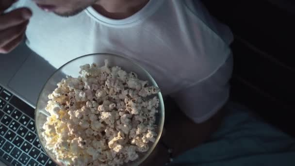Крупный План Молодого Человека Поедающего Попкорн Лежащего Кровати Смотрящего Кино — стоковое видео