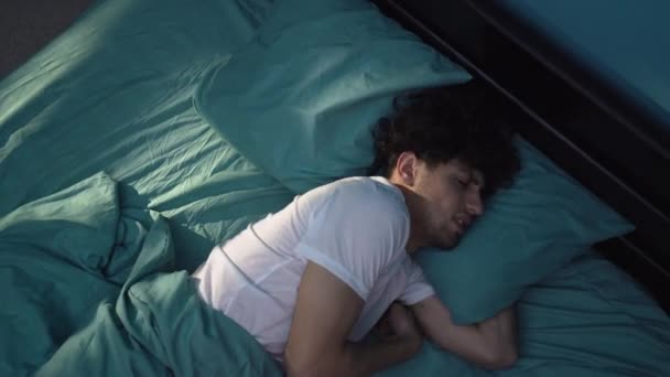 一个心烦意乱的年轻人晚上躺在床上 患有失眠 头枕不响 睡不着觉 复制空间 — 图库视频影像