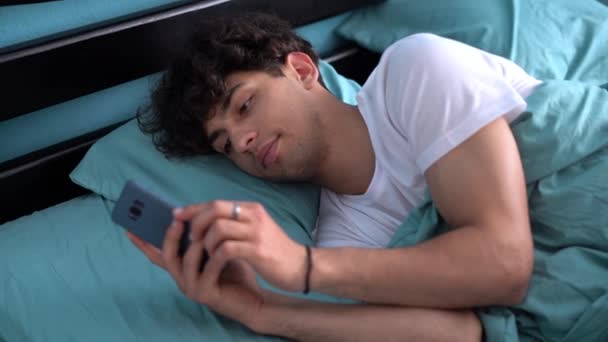 Молодой Человек Использует Смартфон Лежа Постели Утрам — стоковое видео