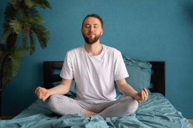 Sabah meditasyon konsepti. Milenyum adamı uyandıktan sonra yatakta yoga yapıyor.