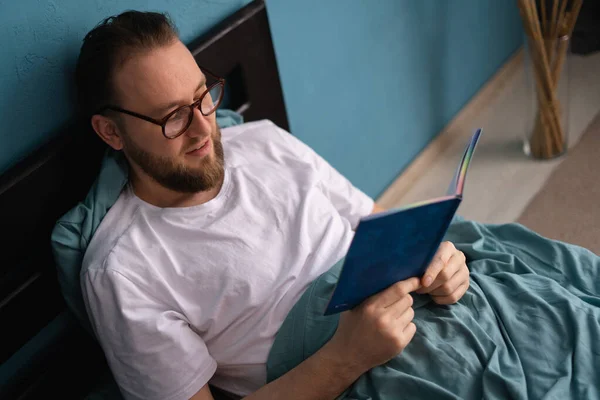 Jonge Blanke Man Draagt Een Bril Leest Een Boek Bed — Stockfoto