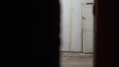 Beyaz çarşaflı bir hayalet terk edilmiş bir eve girer ve kapıdan kameraya bakar. Cadılar Bayramı konsepti