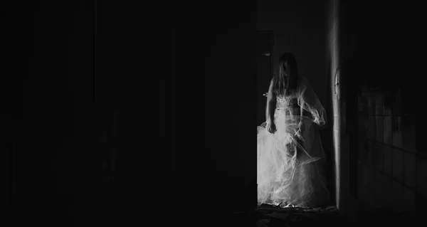 一个被附身僵尸新娘的恐怖场景 穿着白衣的女人在黑暗的房间里拿着干枯的玫瑰 万圣节可怕的概念 班纳复制空间 — 图库照片