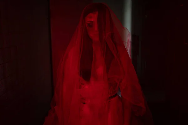 一个被附身新娘的恐怖场景 身穿白衣的女鬼僵尸牵着干玫瑰花束 手牵着红光在黑暗的房间里 万圣节可怕的概念 — 图库照片