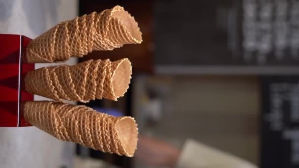 アイスクリームのためのワッフルコーンの山からコーンを選択すると カフェ レストランでアイスクリームで満たされる準備ができています カフェやレストランのショーケース 垂直ビデオ — ストック動画
