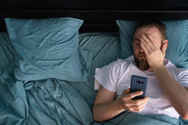 Verward Man Kijkt Naar Mobiele Telefoon Liggend Bed Thuis Ochtend — Stockfoto