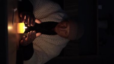 Evde elinde mumla elektriği olmayan yaşlı bir adam. Isıtma ve elektriğin kesilmesi, elektrik kesintisi, elektrik kesintisi, karartma, yük boşaltma veya enerji krizi. kopyalama alanı. Dikey video
