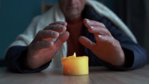 Mrznoucí Stařec Zimním Oblečení Zahřívá Ruce Hořící Svíčce Vypnutí Vytápění — Stock video