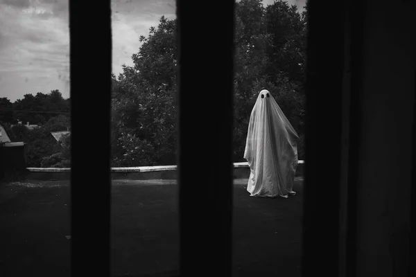 老房子屋顶上的一张单子上的鬼魂朝大窗户看去 黑白照片 复制空间 — 图库照片