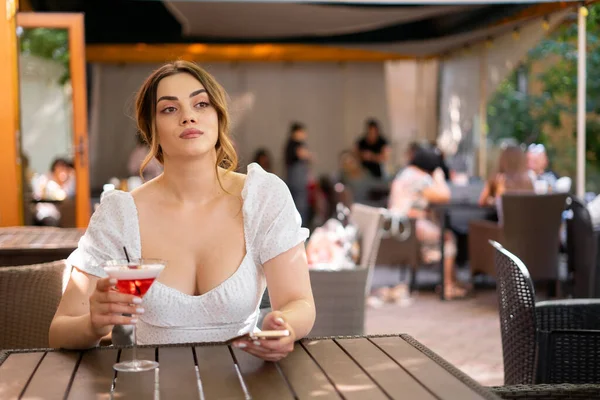 夏には都会のレストランテラスで友人と会うのを待っている間 美しいかわいい女性がカクテルを飲んでいます 美しい女性は街のアウトドアライフスタイルをお楽しみください スペースのコピー — ストック写真