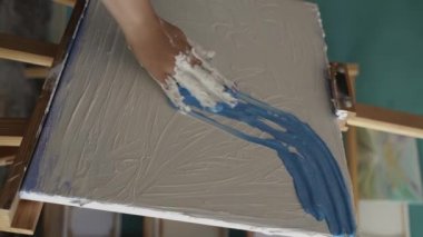 Sanat stüdyosunda kadın ressam tuvale kalın bir desen boyası çiziyor. Yakın plan. Dikey video