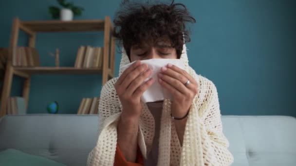 病気の男は自宅でソファに座って鼻を吹いてインフルエンザに苦しんでいる — ストック動画